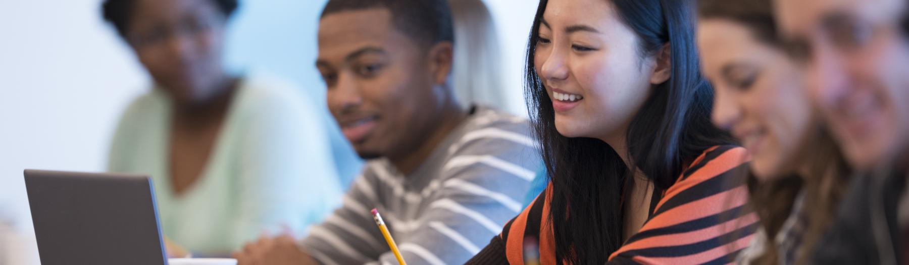 Schülerinnen und Schüler schauen auf ein Notebook